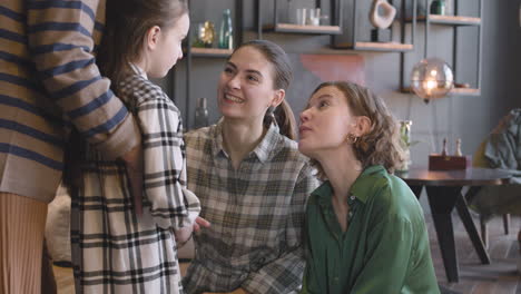 little girl talking with her mother and aunt while unrecognizable grandmother hugging her from behind during a family reunion at home