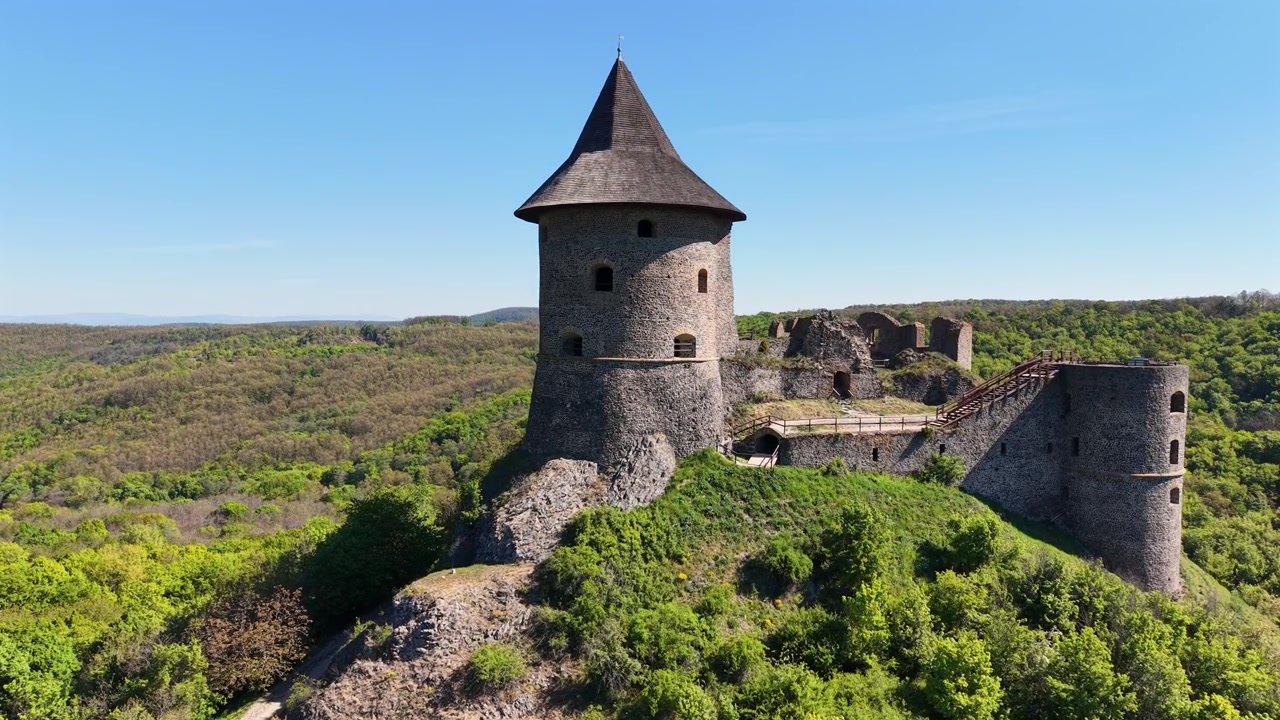 Pemandangan udara yang indah dari menara Kastil Somoska yang bersejarah di Slovakia. Struktur batu abad pertengahan ini berdiri megah di tengah hutan hijau.