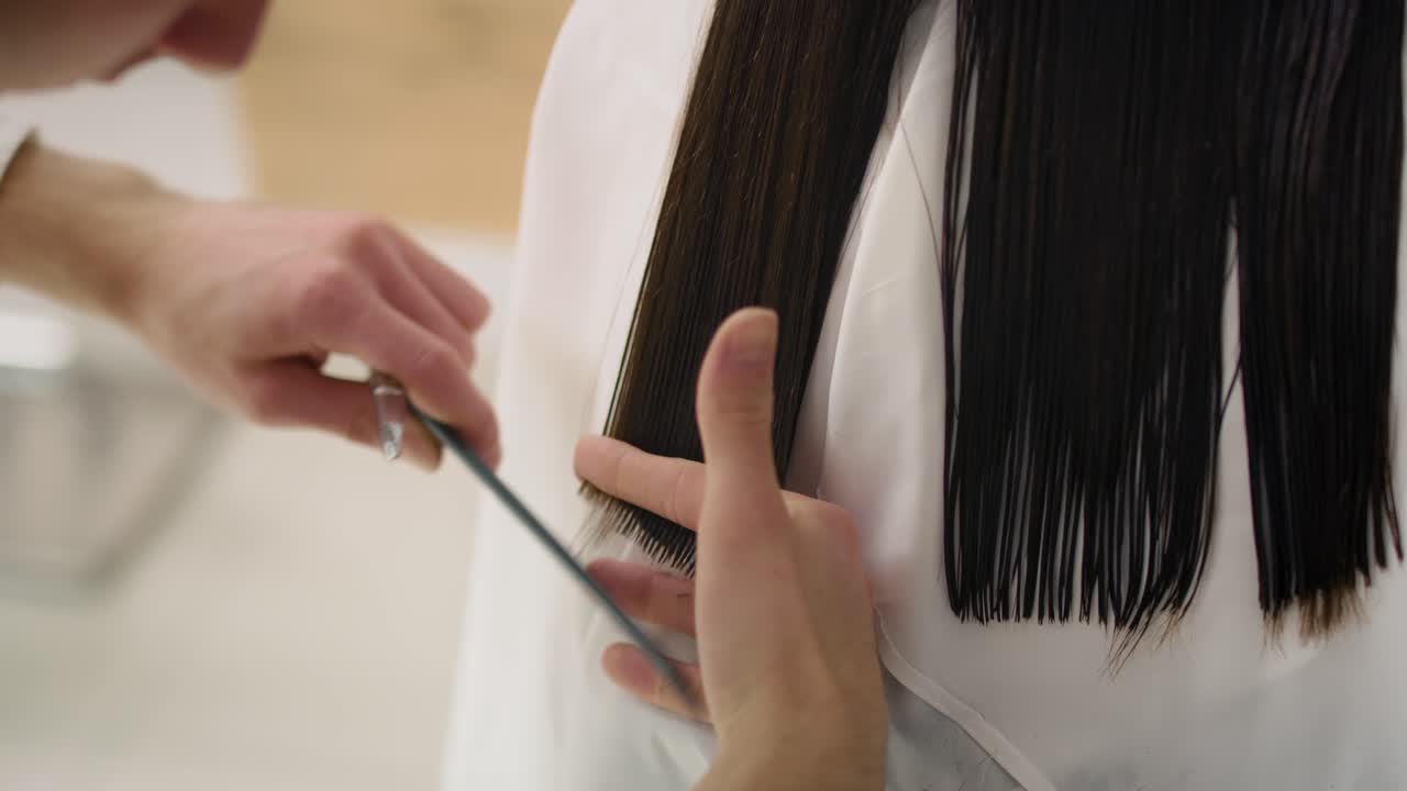 여성의  ⁇ 드헬드 뷰는 이발사에서 머리카락을 자르고 있습니다.
