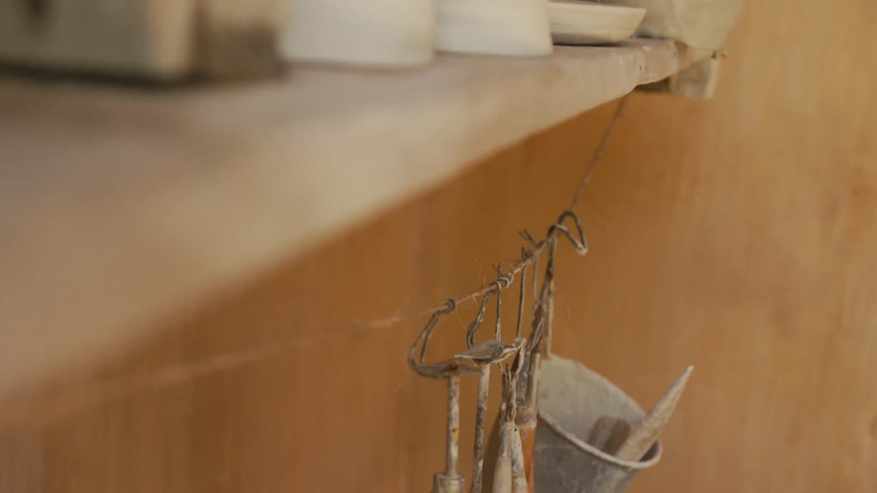 Handmade pots and plates lying on shelf in pottery workshop