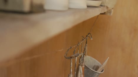 Handmade-pots-and-plates-lying-on-shelf-in-pottery-workshop