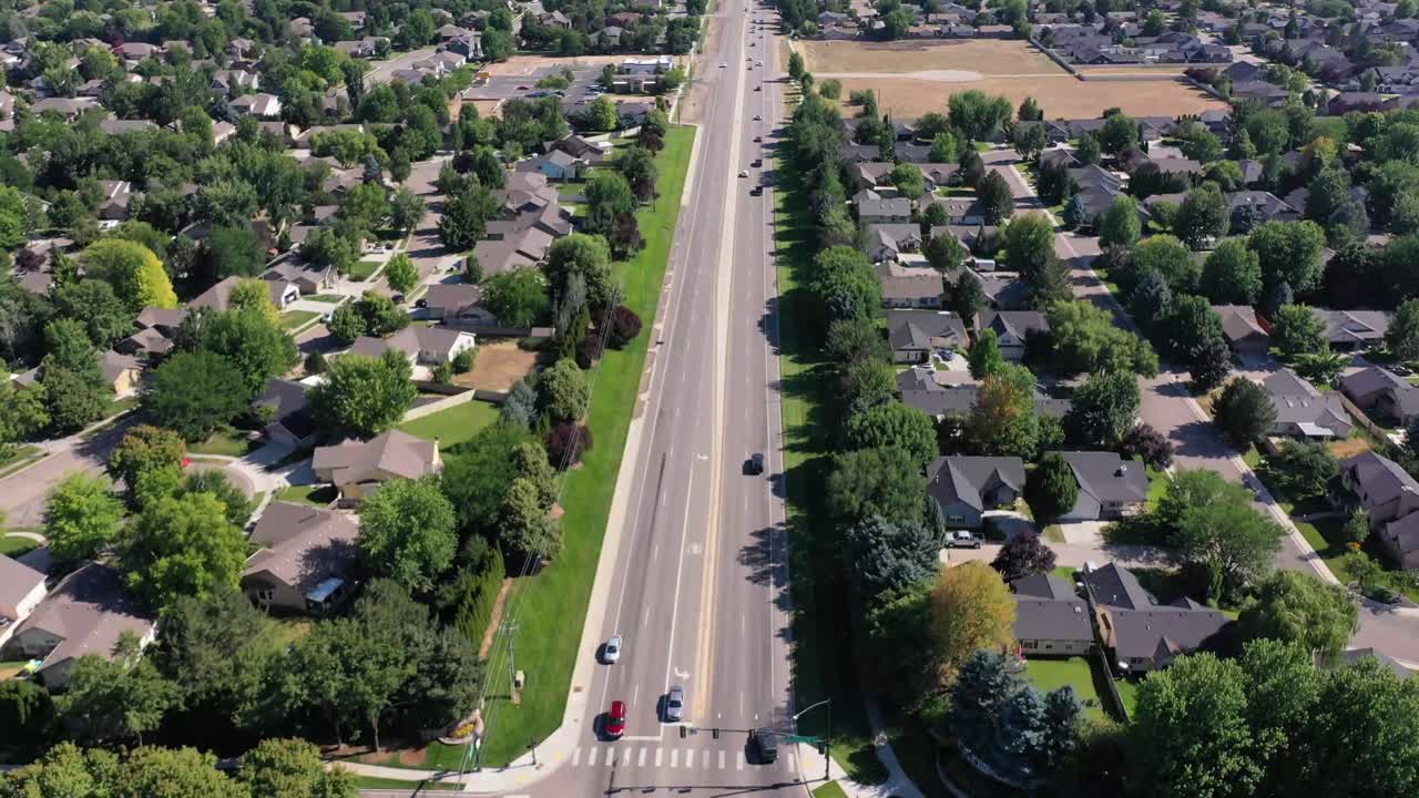 Drone pushes in and tilts down over heavy traffic. There are housing and businesses blanketing the city.
