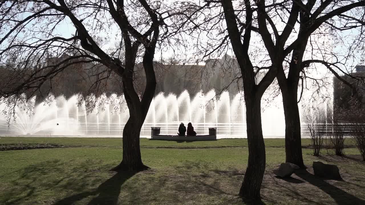 Couple Relaxing by a Fountain in a City Park