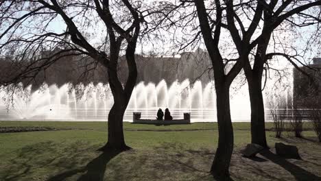 couple relaxing by a fountain in a city park