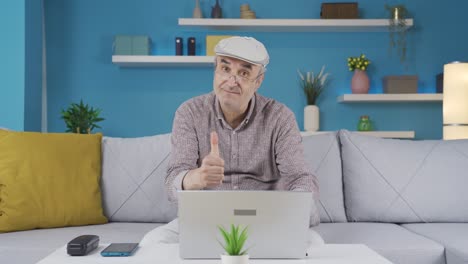 hombre anciano usando una computadora portátil mira a la cámara y hace un gesto positivo.