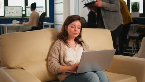 Manager-woman-searching-on-laptop-sitting-in-relax-zone-on-confortable-couch