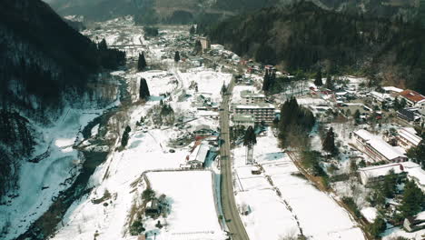 Drone-lifting-shot-of-Japanese-village-covered-in-snow-in-Okuhida,-Japan