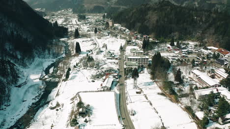 drone lifting shot of japanese village covered in snow in okuhida, japan