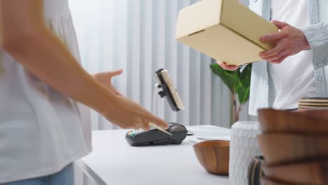 close up hands of young woman use credit card pay for vase goods order. attractive female customer making a easy and quick contactless payment for product box from small business in warehouse store.