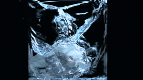 two ice cubes falling into glass on black background