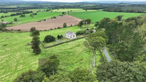 Pequeña-Iglesia-Y-Cementerio-En-Una-Colina-Con-Vistas-A-Las-Fértiles-Tierras-Verdes-De-Irlanda