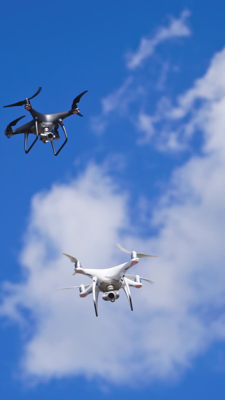 Drones hovering across the sky. Two drone quad copters with high resolution digital camera flying Vertical video