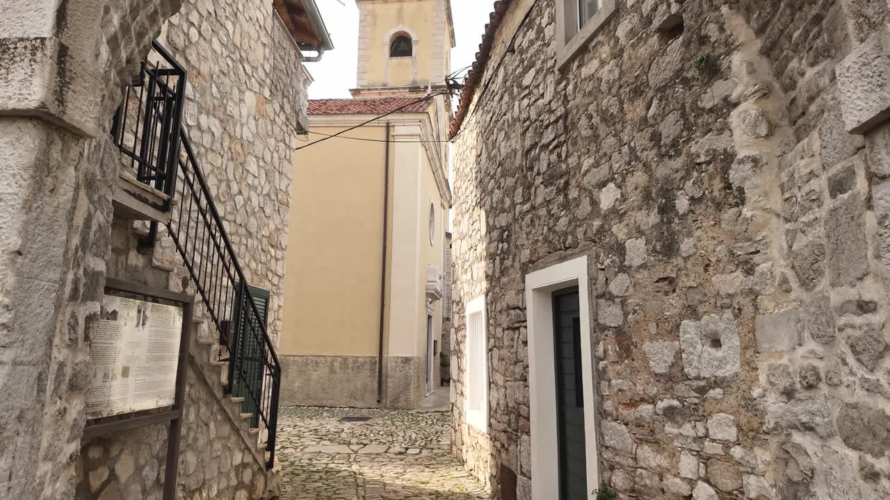 Passeggiando sotto il cancello ad arco in pietra di Pirovac, un tempo ingresso fortificato contro le forze ottomane. Viaggio in Croazia