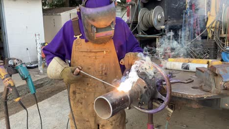 close-up shot of an experienced welder welding a pipe outside