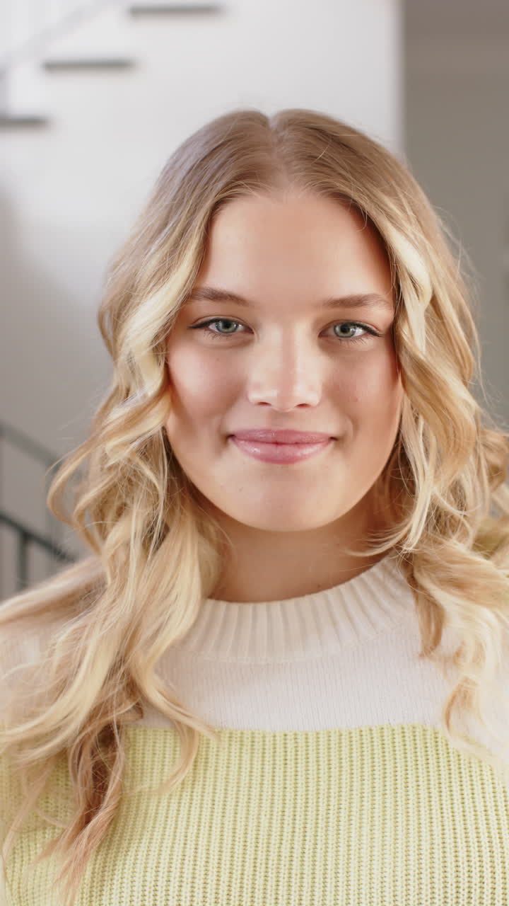 Vertical video of portrait of happy caucasian woman with blonde hair, smiling at home, slow motion