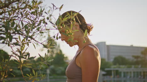 cuerpo delgado de mujer deportista estirándose en el parque de la luz del sol de primer plano. mujer levantando las manos