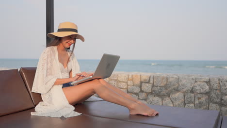 Mujer-Asiática-Feliz-Usando-Una-Computadora-Portátil-En-La-Playa-Durante-Las-Vacaciones-De-Viaje