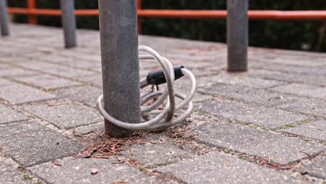 stolen bicycle broken lock cable attached to metal bike stand pole