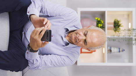 Vertical-video-of-The-old-man-texting-on-the-phone-is-frustrated.