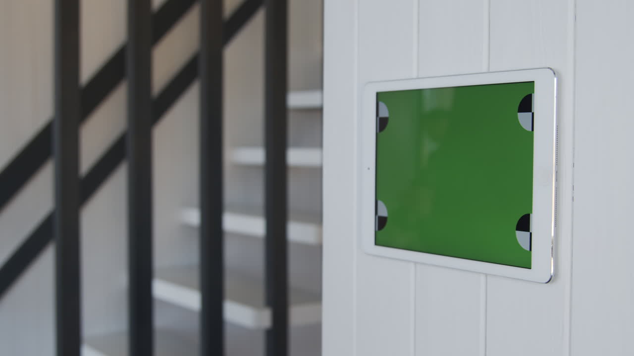 녹색 화면 을 가진 벽 에 장착 된 태블릿 을 사용하는 젊은 여자