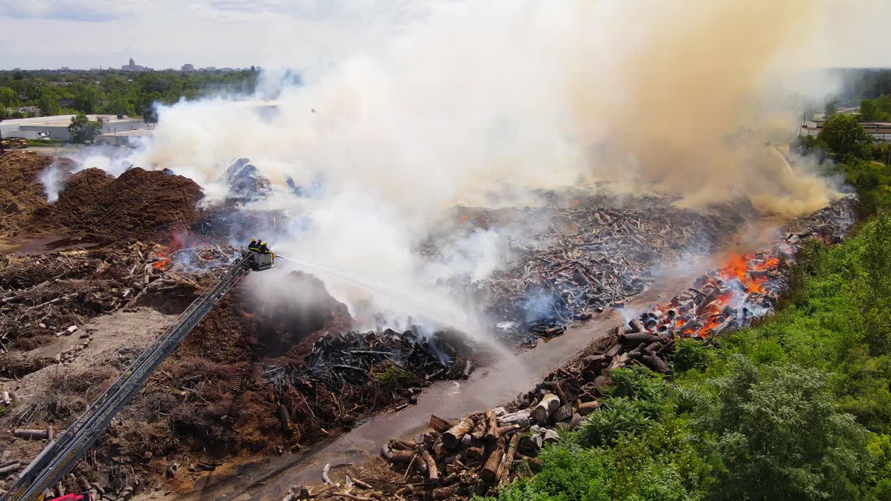 Massive fire in Mulch company with huge smoke and firefighters, aerial view