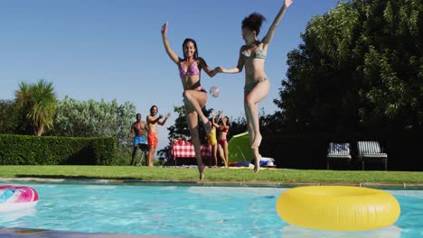 un grupo diverso de amigos divirtiéndose saltando a una piscina