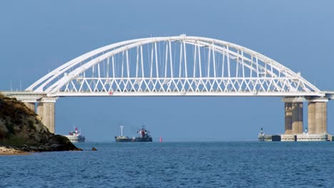 white arch bridge over waterway with ships