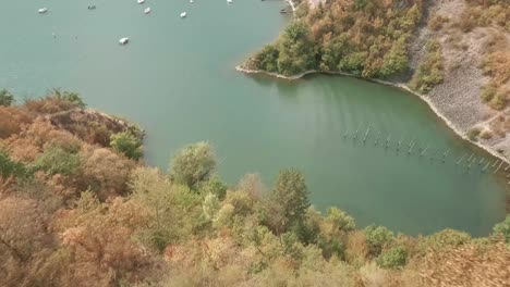 Flying-with-FPV-racing-drone-down-a-tree-covered-hill-and-above-a-bay-full-of-parked-yachts-and-sailboats-on-the-lake-Zemplinska-sirava-in-Eastern-Slovakia