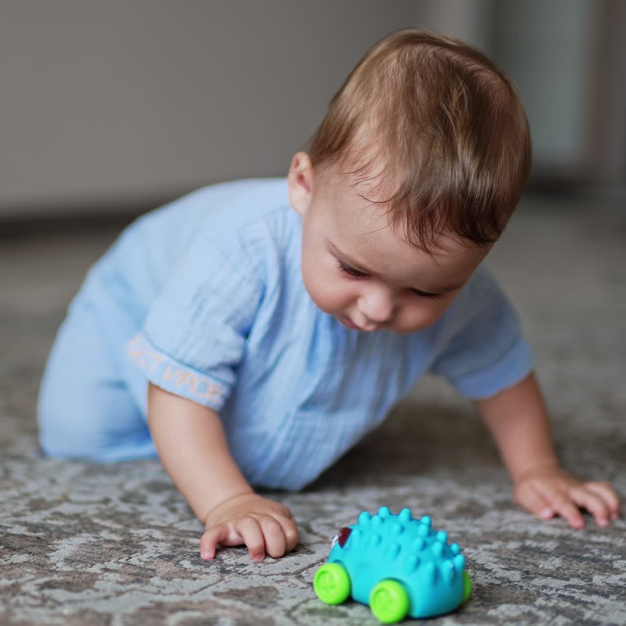 Healthy cute kid playing on the floor. Funny boy moves actively and smiling adorably. Close up. Blurred backdrop