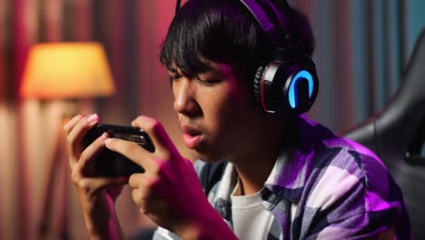 close up of asian teen boy gamer lose while playing video game on smartphone