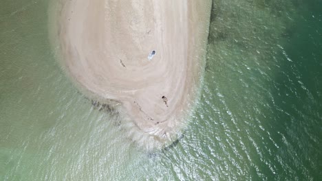 Ascending-aerial-view-of-a-young-woman-laying-on-the-white-sand-beach-of-No-Man-Land,-Tobago