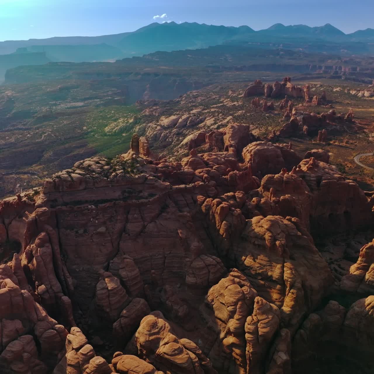 Sunlit canyon mountains in Arches National park in Utah, United States. Rising over the amazing rocks on the uneven landscape