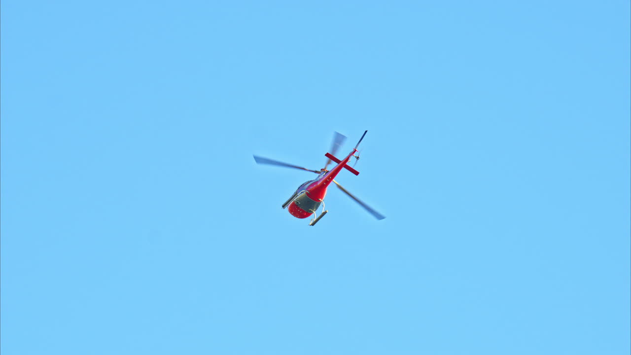 Red helicopter moving in the sky in daylight