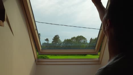 residente cerrando la ventana abuhardillada de su cabaña bajo el cielo nublado