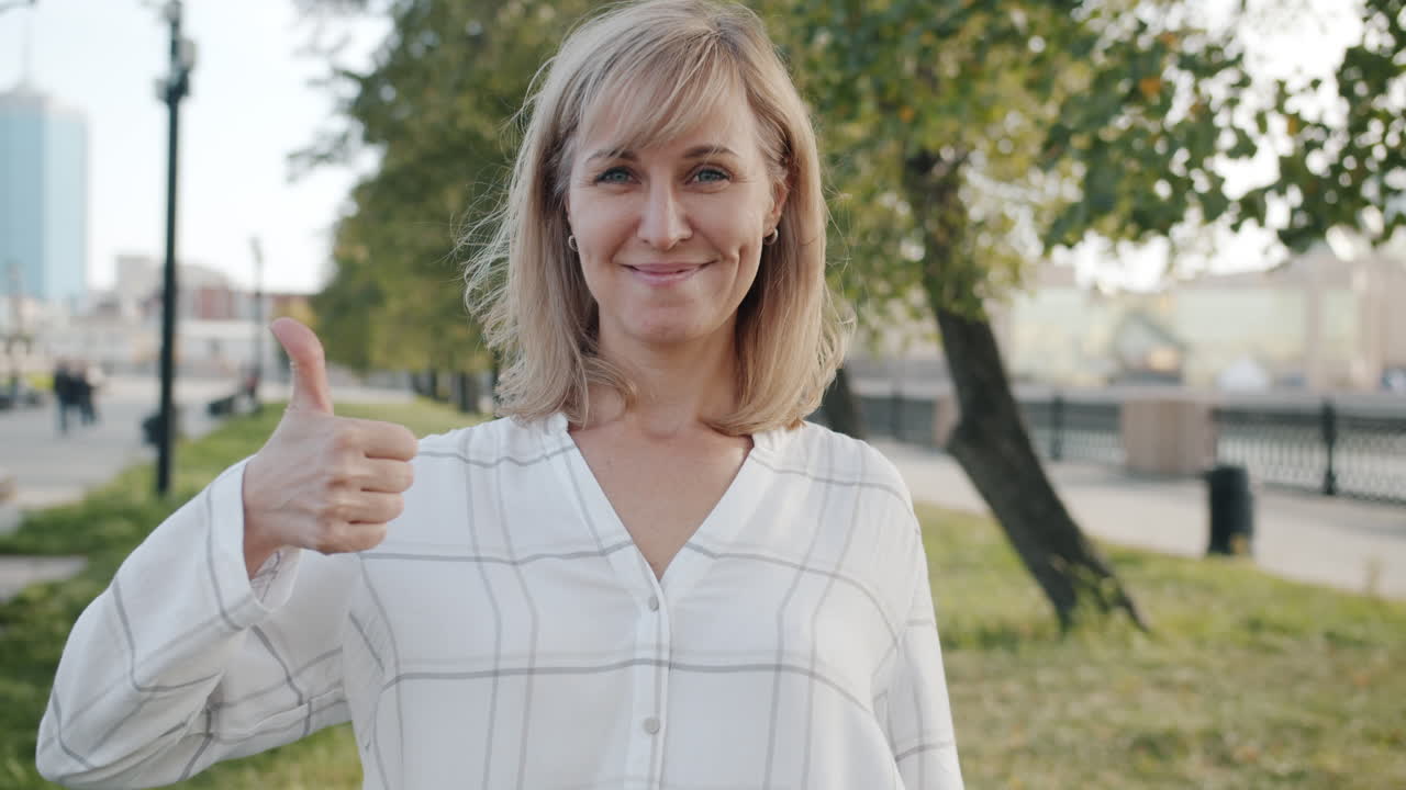 Woman giving thumbs up in city park