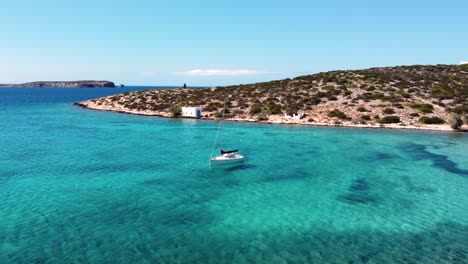 aerial of sailing boat in agia irini paradisiacal turquoise waters beach bay, paros