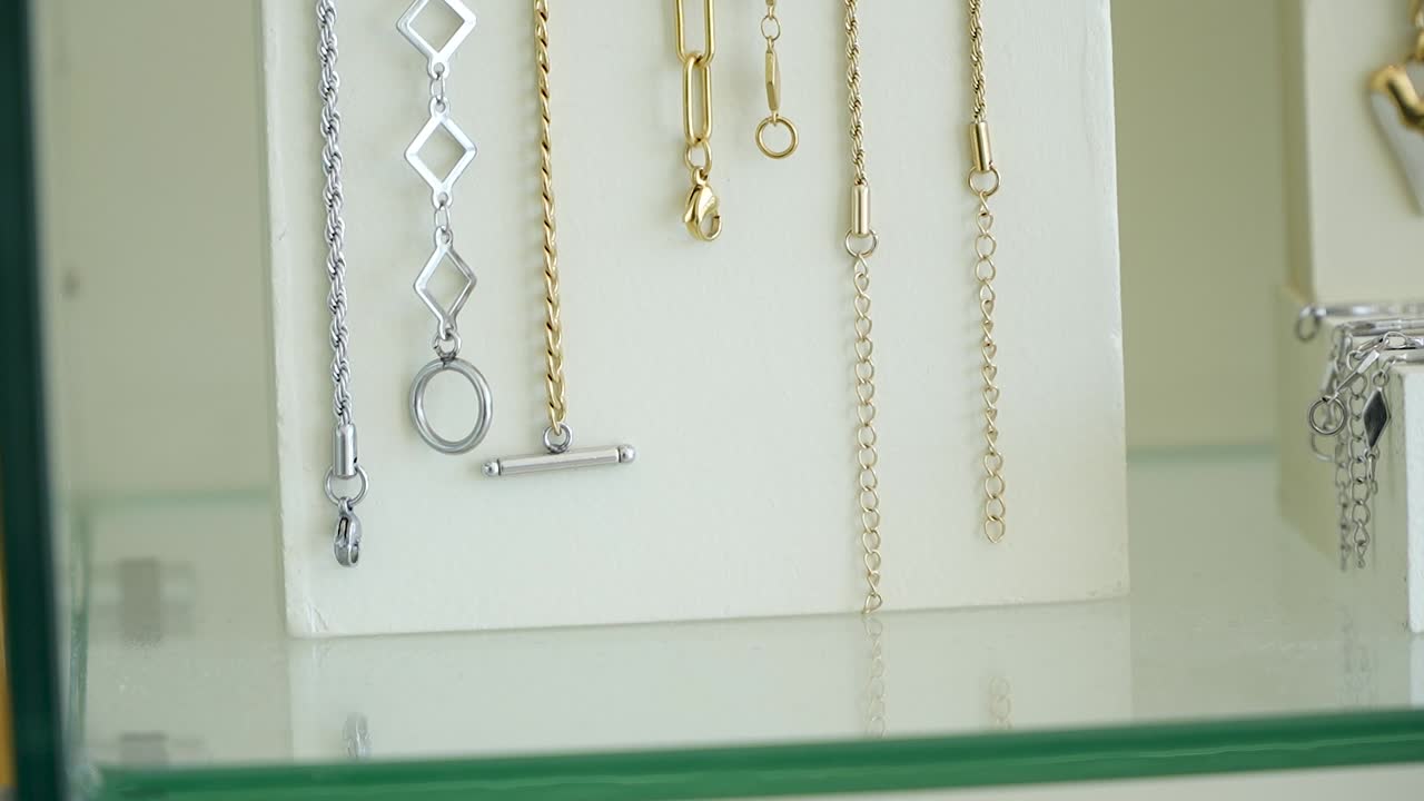 A close-up view of elegant necklaces and chains in a boutique shop, highlighting their shiny metal and intricate designs under natural light
