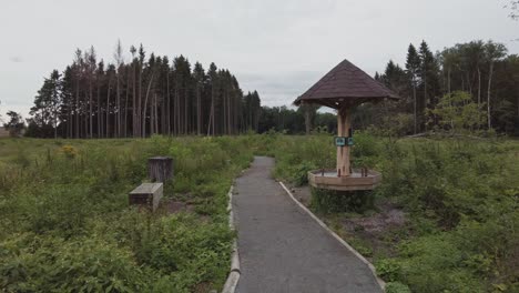 Walking-along-a-gravel-walkway-slowly-approaching-a-structure-with-a-wooden-bench-close-by