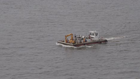 small vessel collecting trash on gray waters of hamburg's harbor, overcast day, mid-shot