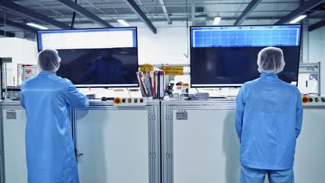 modern manufacturing background. workers in protective clothing inside the industrial factory. specialists look at computer monitors at advanced factory.