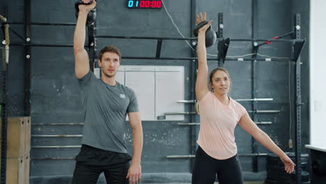 couple working out with kettlebells in a gym