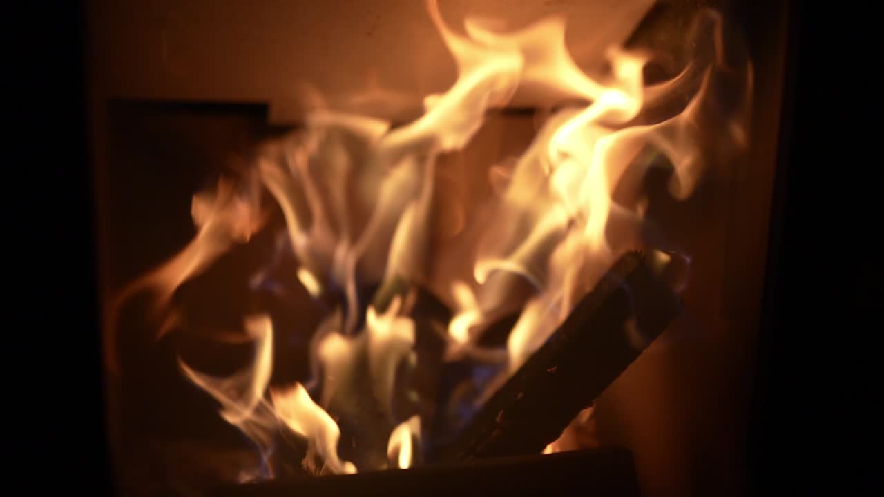 Flickering flames in a fireplace with logs burning and smoke rising