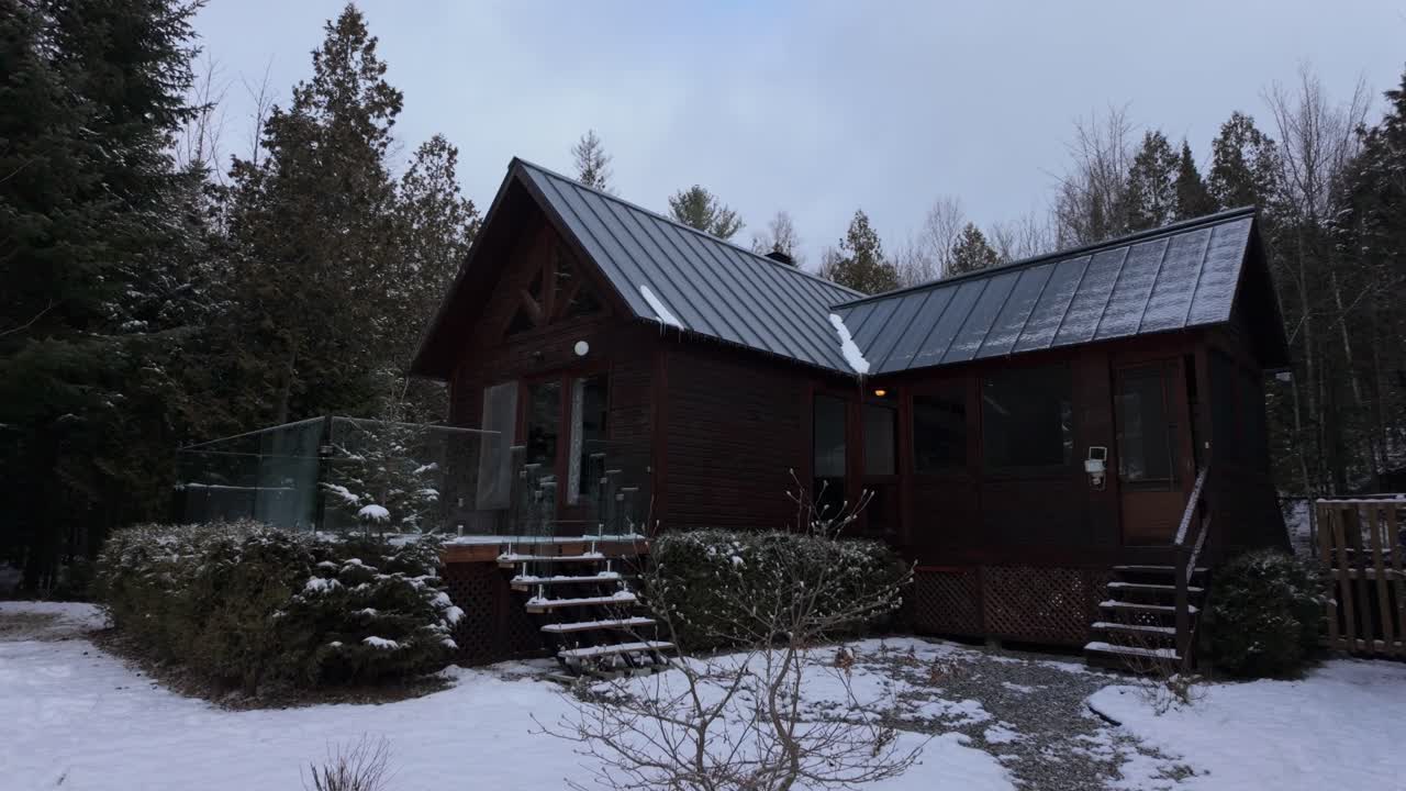 캐나다 페티-체르시 (petit-chertsey) 의 클레르무스티어 호수 근처의 눈 인 풍경에 자리잡은 아한 오두막 - 드론이 앞으로 날아갑니다.