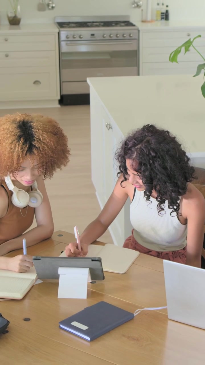 Video verticale: Bionda in movimento con partner dinamici che indicano e prendono appunti al tavolo della cucina con un tablet.