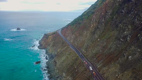 overhead aerial view of a car driving along cliffs of the pacific ocean coast in big sur on state route 1 in california