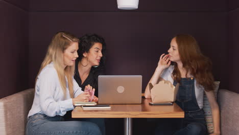 Grupo-De-Jóvenes-Empresarias-Sentadas-Alrededor-De-Una-Mesa-En-Un-Espacio-De-Trabajo-Moderno-Con-Un-Almuerzo-De-Trabajo