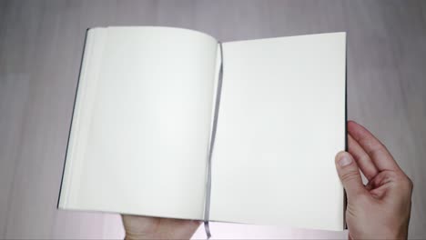 man's hands opening  a blank book.