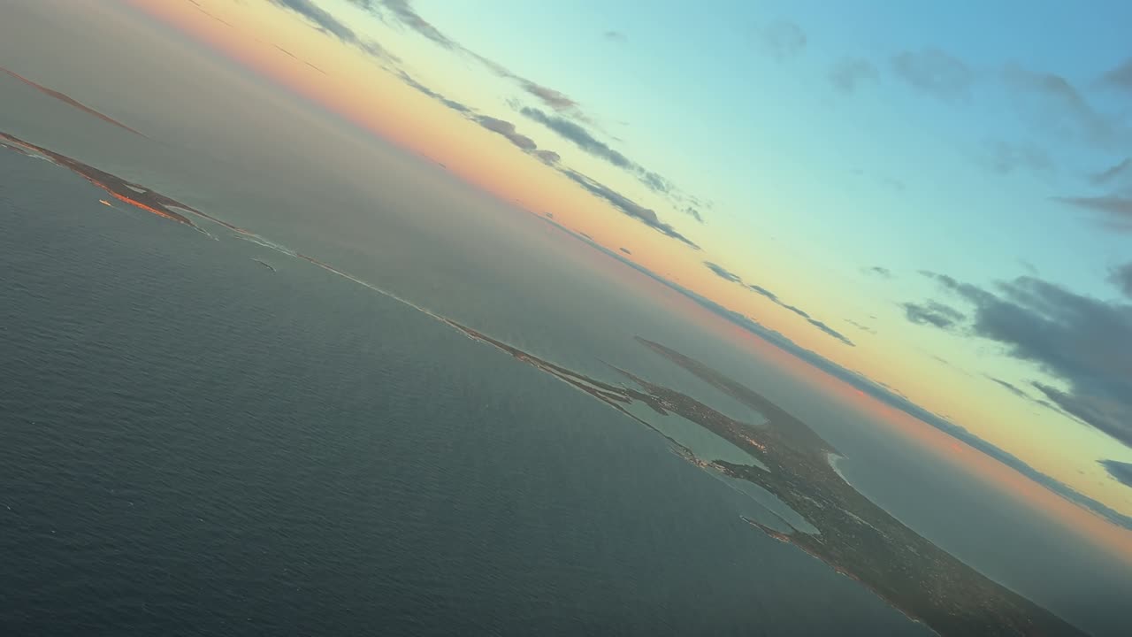 An elevated perspecrtive view of Formentera island captured from an airplane cockpit while doing a left turn over the Mediterranean Sea at Sunrise