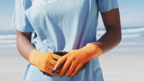 porträt einer afroamerikanischen frau, die ein ehrenamtliches t-shirt und eine gesichtsmaske trägt und in die kamera schaut