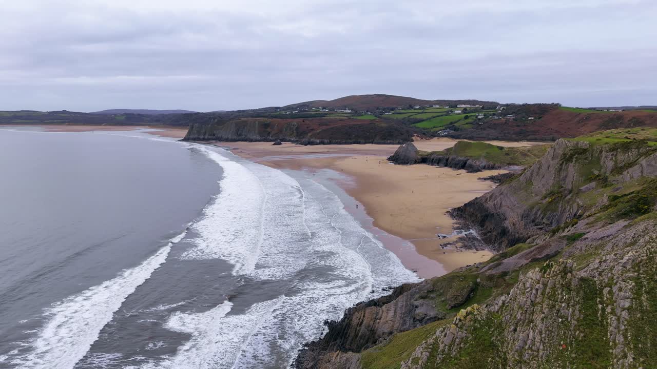 volando sobre la costa de arena dorada de los tres acantilados de la bahía de la península de gower en gales